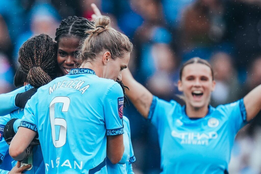 El City, líder virtual. Varias jugadoras del City, entre ellas Bunny Shaw y Vivianne Miedema, abrazan a Mary Fowler tras anotar el segundo gol de la tarde. Al fondo, Kerstin Casparij celebra con los brazos en alto.