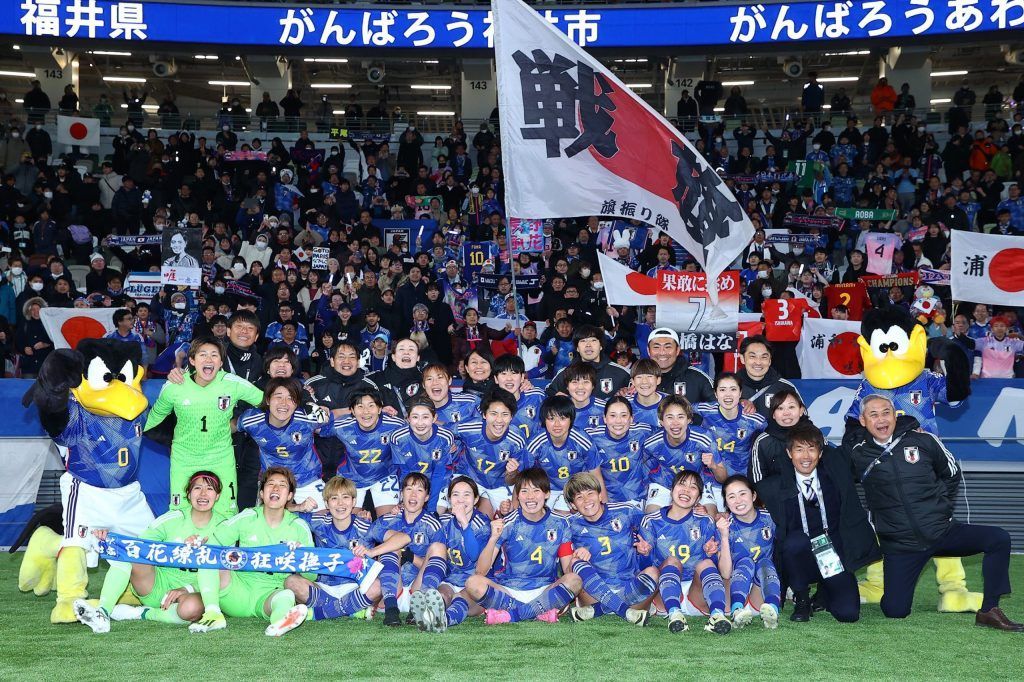 Japón consigue su lugar en los Juegos Olímpicos. Las Nadeshiko posan con las mascotas y sus aficionados celebrando la clasificación.