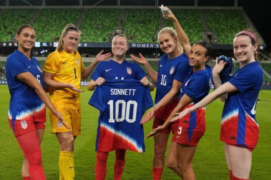 Estados Unidos sigue sumando victorias. Lynn Williams, Alyssa Naeher, Lyndsey Horan, Mal Swanson y Rose Lavelle celebran el homenaje a Emily Sonnett, que sostiene una camiseta conmemorativa por su partido número 100 con la selección.