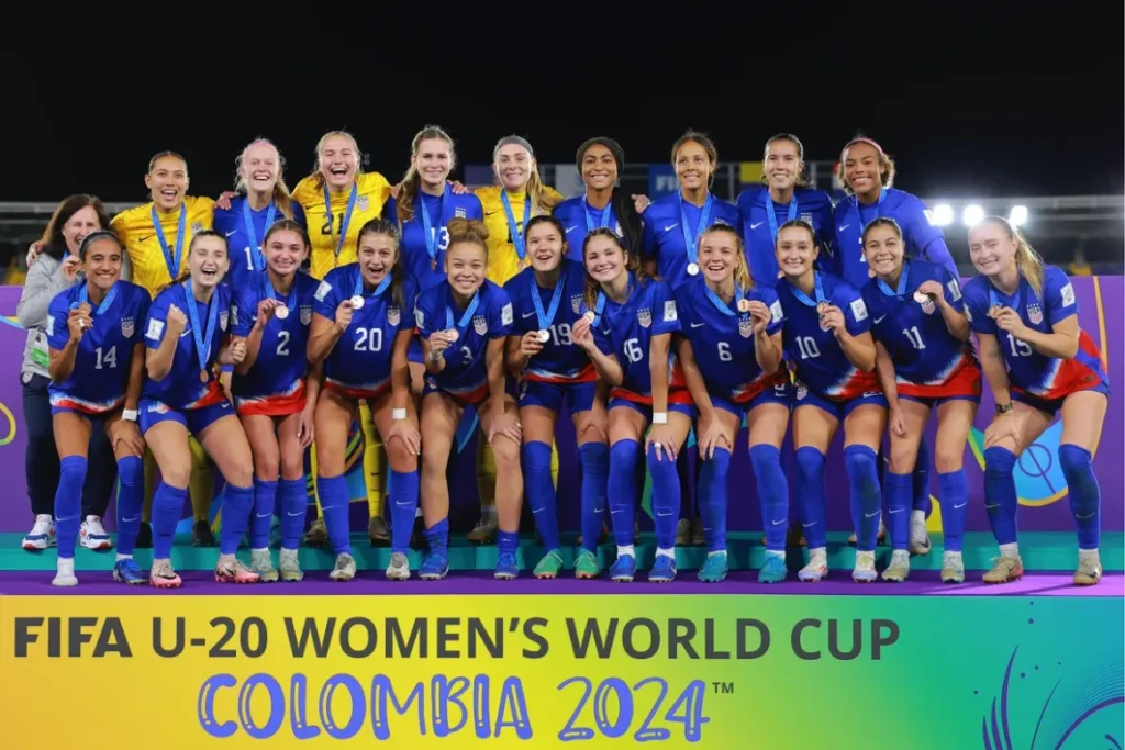 Un autogol le da el bronce a Estados Unidos. Las jugadoras y la seleccionadora estadounidenses posan en el podio con sus medallas.